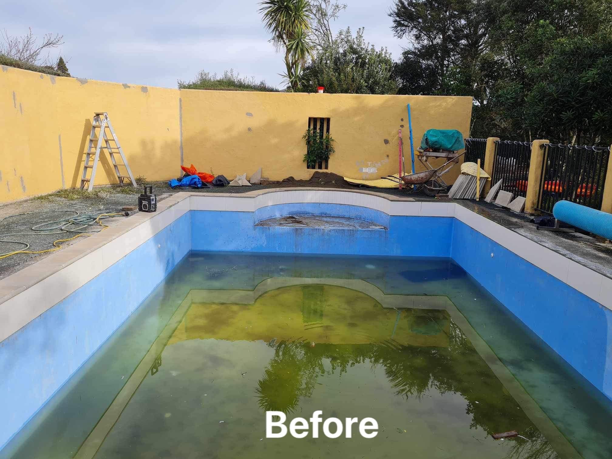 Drained concrete pool with chipped tiles, exposed shell, and scattered debris