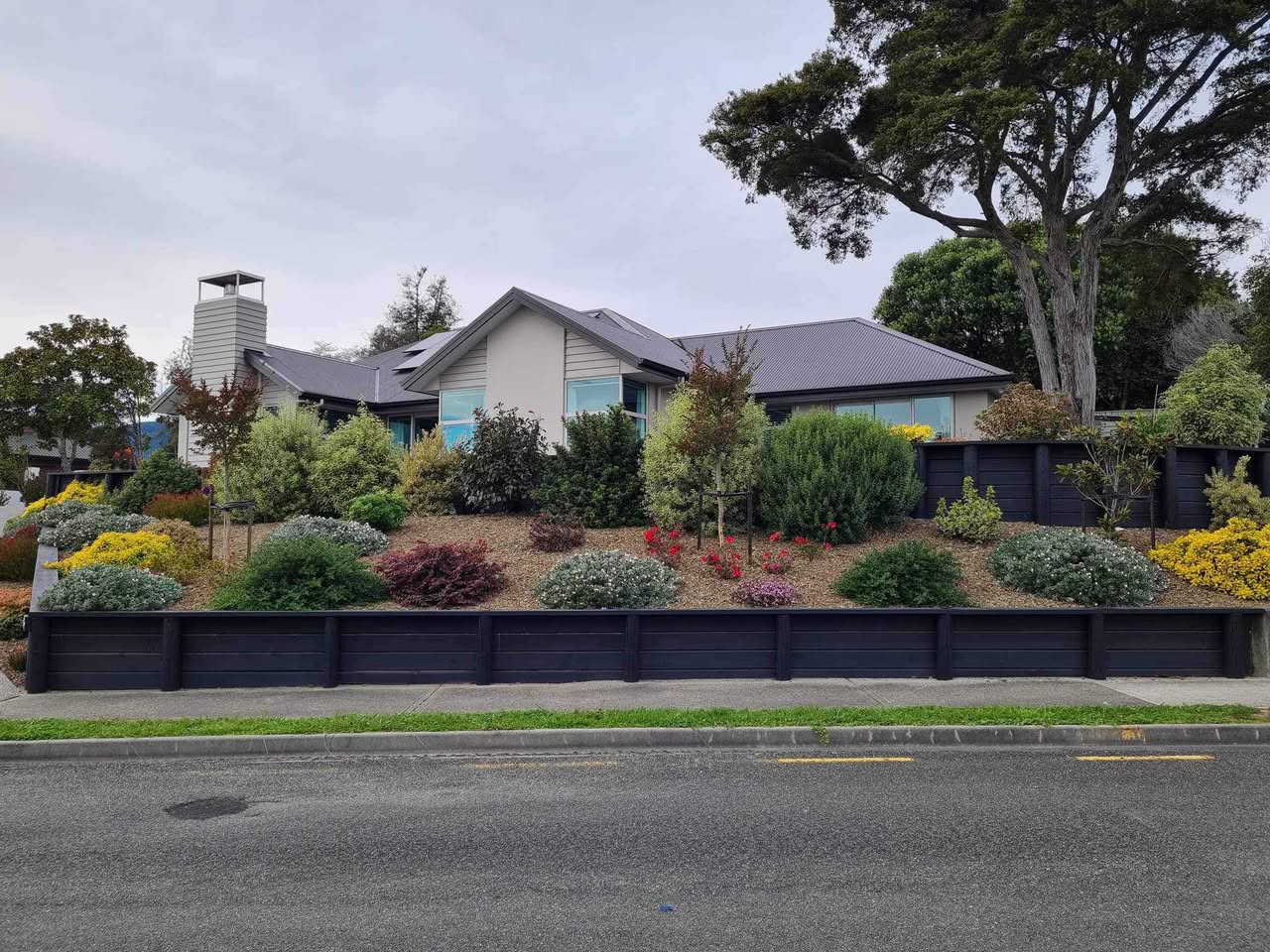 Tiered hillside garden with stone steps, hedging, and outlook over Nelson